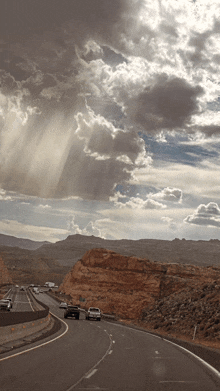 cars are driving down a highway with a cloudy sky behind them