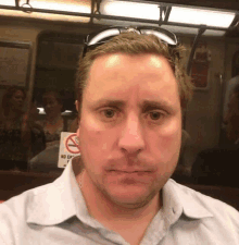 a man sitting on a subway train with a no smoking sign behind him