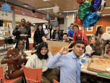 a group of people are posing for a picture with a pizza box in the background