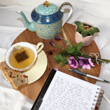 a cup of tea sits on a saucer next to a notebook with handwritten notes