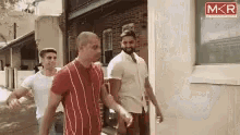 a group of men walking down a street with a mkr logo in the corner