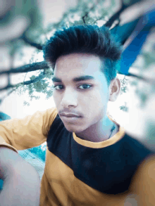 a young man in a yellow and black striped shirt poses for a photo