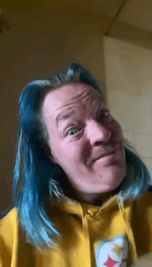 a man with blue hair is wearing a yellow hoodie with a pittsburgh steelers logo