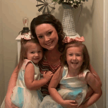 a woman is holding two little girls in her arms