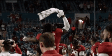 a football player with the number 13 on his back is being lifted in the air