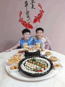 two young boys are sitting at a table with a birthday cake