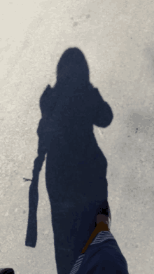 a person 's shadow is cast on a gray surface