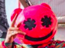 a person is wearing a pink marshmello mask and holding a sword .