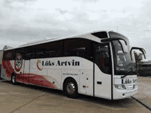 a white and red bus is parked on the side of a road .