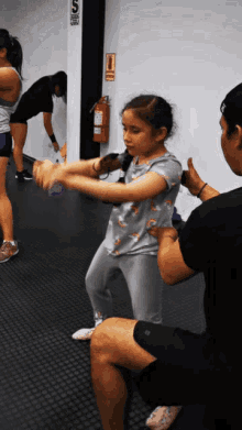 a girl in a gray shirt with a rainbow on it is being held by a man in a gym