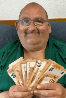 a man is holding a bunch of 50 euro notes