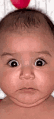 a close up of a baby 's face with a surprised look on his face