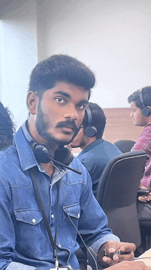 a man wearing headphones and a lanyard is sitting in a chair