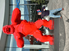 a man stands next to a large red gorilla