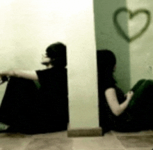 two people are sitting next to each other in a room with a heart drawn on the wall behind them .