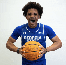 a man wearing a blue georgia state jersey holds a wilson ncaa basketball