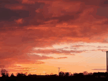 a sunset with a lot of clouds and a telephone pole in the foreground