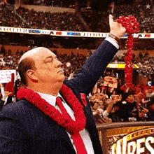 a man in a suit and tie holds up a red garland in front of a crowd with a sign that says wrestlers