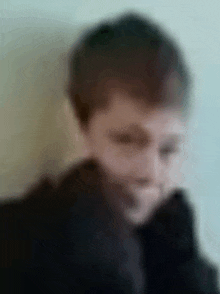 a blurry picture of a person 's face with a black jacket on .