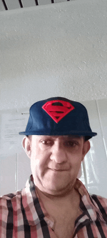 a man wearing a blue hat with a superman logo on it