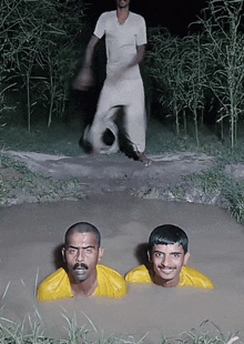 two men in yellow shirts are in a muddy puddle