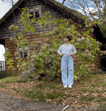 a woman is standing in front of a house with flowers