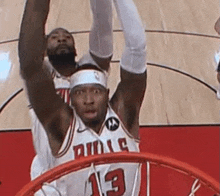 a basketball player in a bulls jersey is going for a dunk .