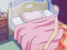 a girl is standing next to a bed with a pink blanket and a pink pillow