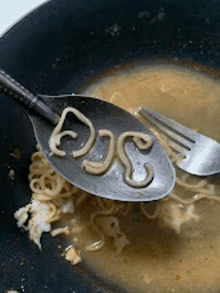 a spoon with noodles written on it is being used to stir a bowl of soup