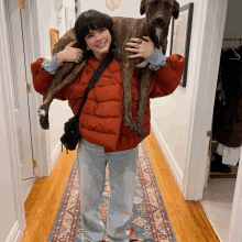 a woman is carrying a dog on her shoulders