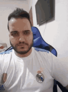 a man with a beard is wearing a white real madrid shirt .
