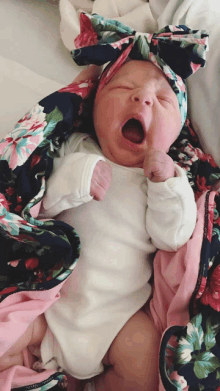 a baby wearing a floral headband yawning