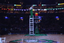 a basketball referee stands on a ladder in front of a scoreboard that says garden on it