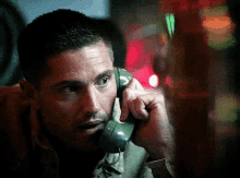 a man talking on a green telephone with a red light in the background