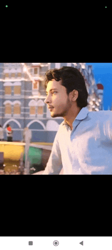 a young man in a blue shirt is standing in front of a building .