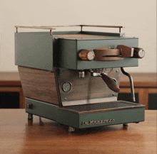 a green la marzocco coffee maker with wooden handles