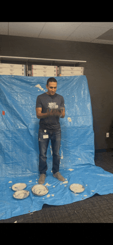 a man wearing a shirt that says " the north face " is standing in front of a blue tarp