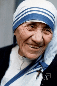 an elderly woman wearing a blue and white striped head scarf smiles