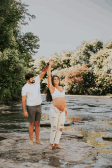 a man and a pregnant woman are holding hands in the air