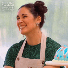 a woman in an apron is smiling in front of a sign that says " the great canadian baking show "