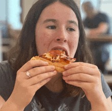 a woman eating a slice of pizza with a ring on her finger