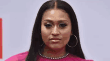 a close up of a woman wearing a pink dress and hoop earrings on a red carpet .