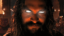 a man with long hair and a beard has glowing red eyes