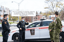 police officers standing in front of a canadian police car