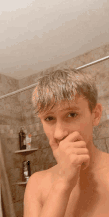 a shirtless young man is taking a selfie in a bathroom