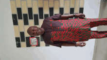 a man standing in front of a brick wall wearing a red shirt