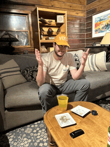 a man sitting on a couch wearing a vols hat