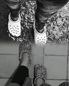 a person wearing a pair of white crocs standing next to another person wearing zebra print crocs