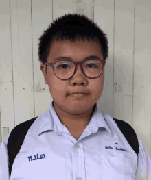 a young boy wearing glasses and a white shirt with the name t.p.d. on it