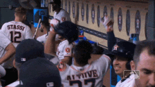 a group of baseball players are sitting in a dugout and one of them has the number 27 on his back